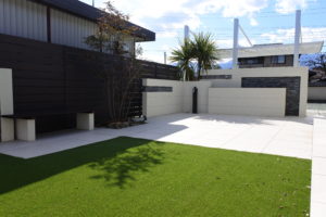 山梨県甲府市の外構施工例。高級感のある大判タイル門柱と、その脇を彩る雑木の植栽、割栗石が調和したナチュラルモダンなアプローチ。