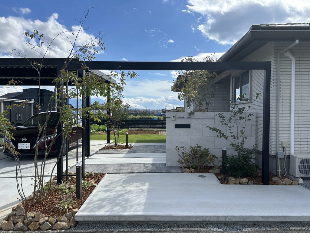 黒のカーポートが空間を引き締め、エントランスの『Gフレーム』が駐車場と住宅との空間を繋ぎ、統一感を高めています。