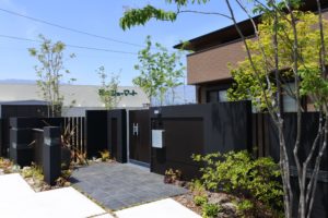 山梨県甲府市の外構施工例。アオダモやモミジなどの雑木の庭と、自然な質感の割栗石が調和したナチュラルな玄関アプローチ。