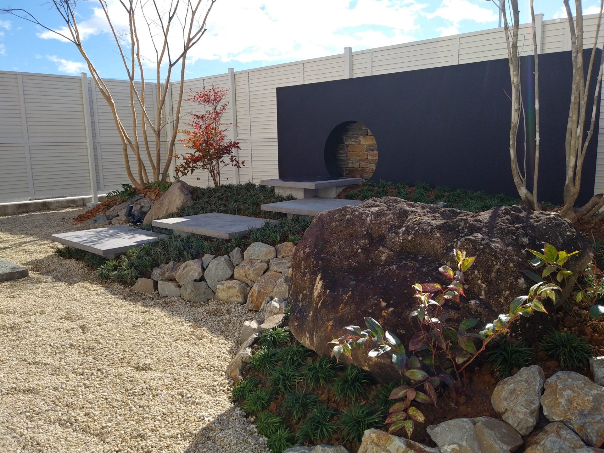 山梨県甲府市の外構施工例。黒い外壁の住宅に映える雑木の庭と割栗石。和風モダンとナチュラルが融合したエントランス。