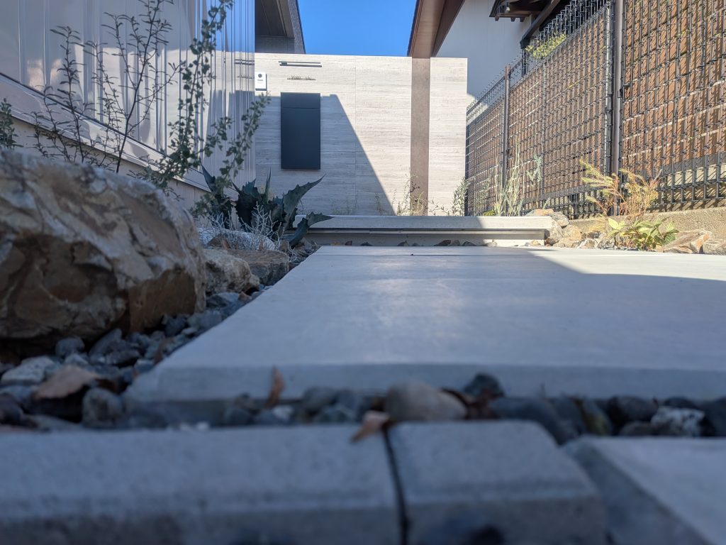 山梨県甲府市の外構施工例。積水ハウスの建物に合わせたタカショーのセラウォールと、アガベ、雑木、ボーダーブリックが調和したモダンエントランス。