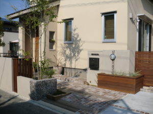 山梨県甲府市の外構施工例。直線的なモダンデザインと、雑木や割栗石の緑が調和したナチュラルモダンなアプローチ。